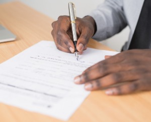 Image of man hands signing paperwork.